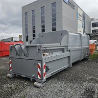 Abrollpresscontainer ohne HKV in Grau RAL 9006 auf Lagerplatz vor Industriegebäude – robuste Lösung für Abfallverdichtung im gewerblichen Einsatz.