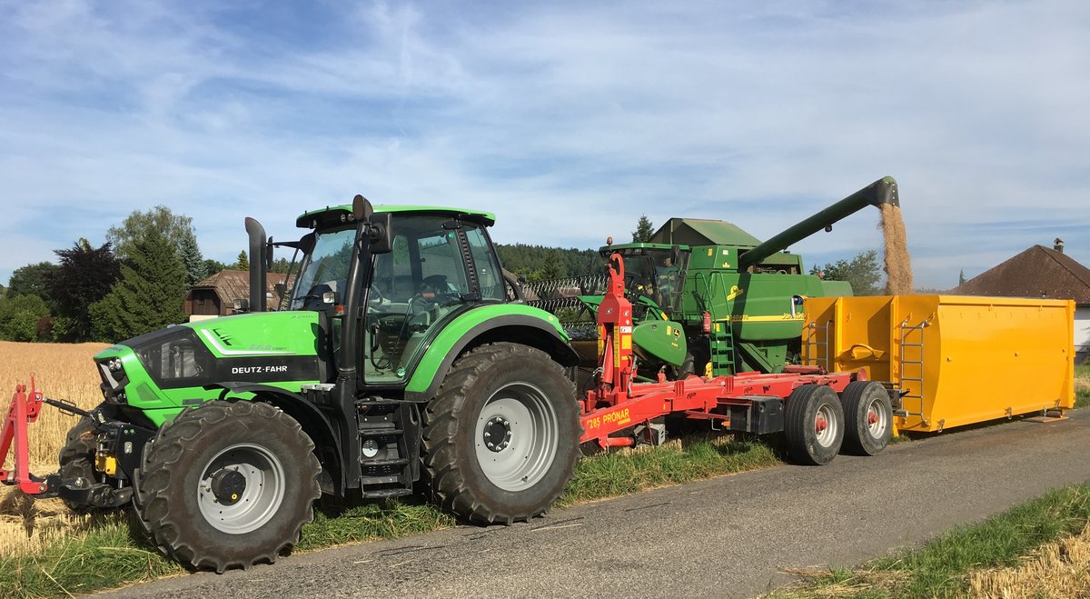 Abrollcontainer mit 36 m³ Volumen, spantenfrei, aus der Serie EKO1 in Gelb, während der Befüllung durch einen Traktor